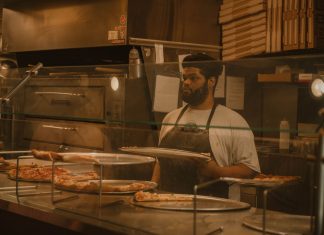 Pizza chef serving slices in a Milwaukee pizzeria, captured in warm tones.