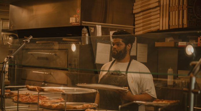Pizza chef serving slices in a Milwaukee pizzeria, captured in warm tones.