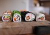 Close-up of assorted sushi rolls on a wooden board showcasing fresh ingredients.