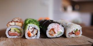 Close-up of assorted sushi rolls on a wooden board showcasing fresh ingredients.