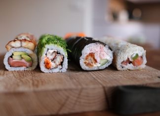 Close-up of assorted sushi rolls on a wooden board showcasing fresh ingredients.