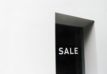 A minimalist black and white image of a sale sign on a store window with ample negative space.