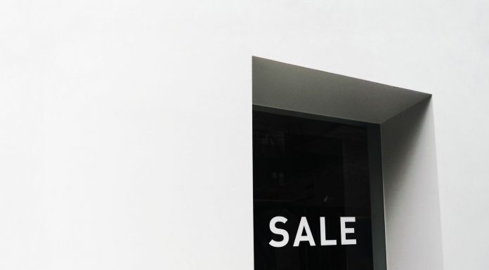 A minimalist black and white image of a sale sign on a store window with ample negative space.