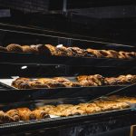 A variety of freshly baked pastries and breads in a glass display case at a bakery.