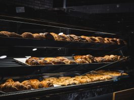 A variety of freshly baked pastries and breads in a glass display case at a bakery.