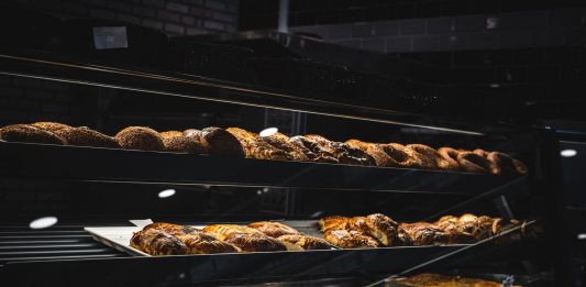 A variety of freshly baked pastries and breads in a glass display case at a bakery.