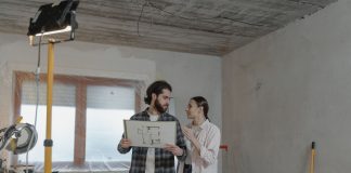BREAKING: Heights Building Gets City Approval for Full Renovation A couple reviews a blueprint in a partially renovated room, planning home improvements.