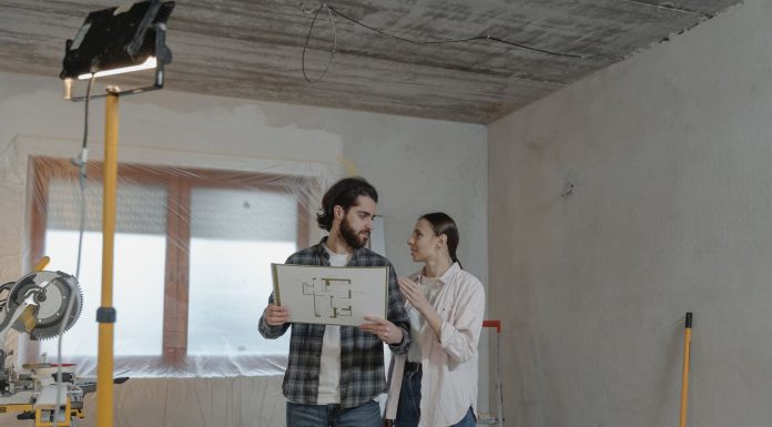 A couple reviews a blueprint in a partially renovated room, planning home improvements.
