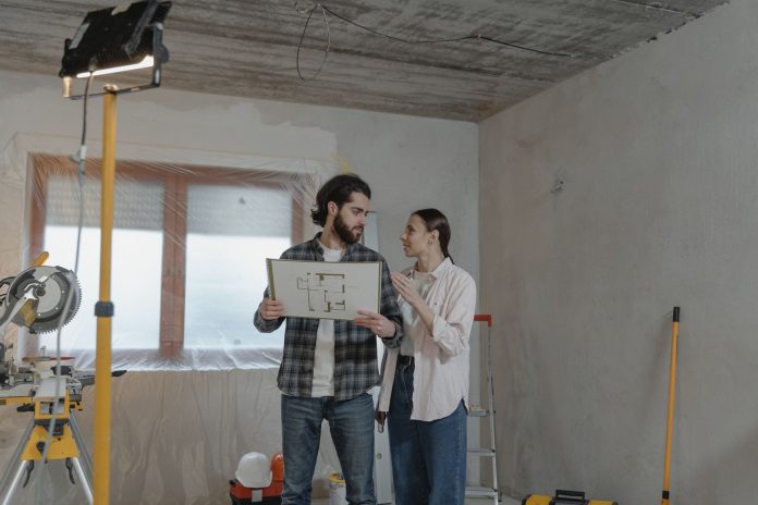 breaking-heights-building-gets-city-approval-for-f A couple reviews a blueprint in a partially renovated room, planning home improvements.
