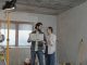 A couple reviews a blueprint in a partially renovated room, planning home improvements.