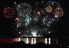 Dazzling fireworks display over Vancouver's waterfront at night, reflecting on the water.
