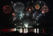 Dazzling fireworks display over Vancouver's waterfront at night, reflecting on the water.