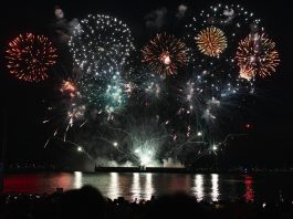 Dazzling fireworks display over Vancouver's waterfront at night, reflecting on the water.