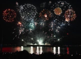 Dazzling fireworks display over Vancouver's waterfront at night, reflecting on the water.