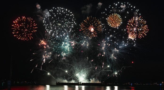 Dazzling fireworks display over Vancouver's waterfront at night, reflecting on the water.