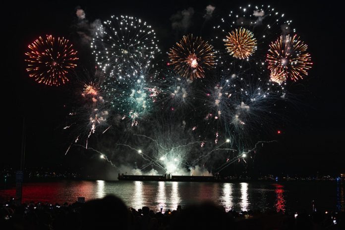 breaking-hoboken-revives-river-city-fair-on-waterf Dazzling fireworks display over Vancouver's waterfront at night, reflecting on the water.