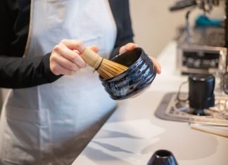 BREAKING: Jane’s Matcha Opens First Brick-and-Mortar in Jersey City Close-up of a person preparing matcha tea using a bamboo whisk and bowl indoors.