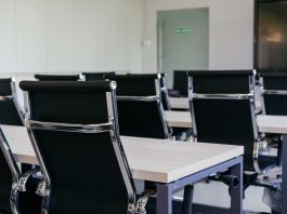 Sleek modern conference room with black chairs and white desks, suitable for business meetings.