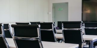 Sleek modern conference room with black chairs and white desks, suitable for business meetings.