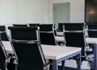 Sleek modern conference room with black chairs and white desks, suitable for business meetings.
