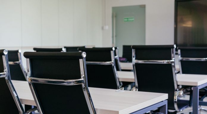 Sleek modern conference room with black chairs and white desks, suitable for business meetings.