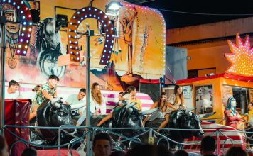 People enjoying a vibrant bull ride at an outdoor funfair at night.