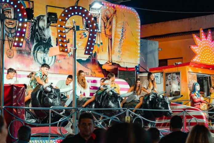 People enjoying a vibrant bull ride at an outdoor funfair at night.
