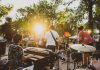 Musicians performing live at a summer outdoor concert during sunset in a park.