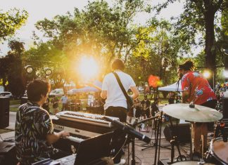 Musicians performing live at a summer outdoor concert during sunset in a park.