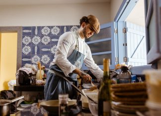 BREAKING: Michelin-Recognized Chef Opens Punjab Meet House in Jersey City A chef in a rustic kitchen cooks a gourmet meal with an open door filling the room with natural light.