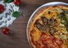 BREAKING: New Weekly Recipe Series Launches for Hudson County Close-up of homemade pizza with fresh vegetables and herbs on a wooden table.