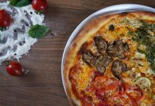 BREAKING: New Weekly Recipe Series Launches for Hudson County Close-up of homemade pizza with fresh vegetables and herbs on a wooden table.