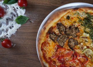 BREAKING: New Weekly Recipe Series Launches for Hudson County Close-up of homemade pizza with fresh vegetables and herbs on a wooden table.