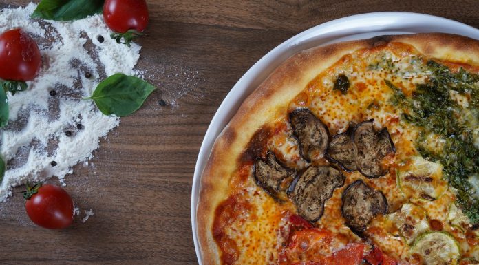BREAKING: New Weekly Recipe Series Launches for Hudson County Close-up of homemade pizza with fresh vegetables and herbs on a wooden table.