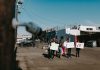 A group of diverse protesters peacefully demonstrating with signs in an open urban space.