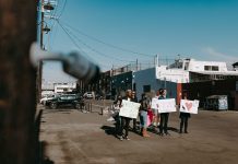 A group of diverse protesters peacefully demonstrating with signs in an open urban space.