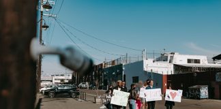 A group of diverse protesters peacefully demonstrating with signs in an open urban space.