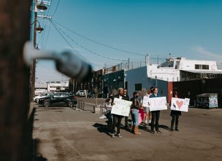 A group of diverse protesters peacefully demonstrating with signs in an open urban space.