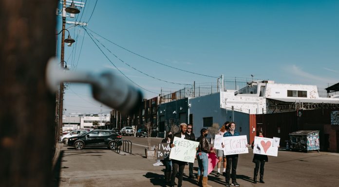 A group of diverse protesters peacefully demonstrating with signs in an open urban space.