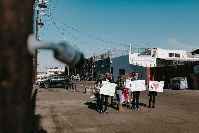 A group of diverse protesters peacefully demonstrating with signs in an open urban space.