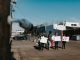A group of diverse protesters peacefully demonstrating with signs in an open urban space.