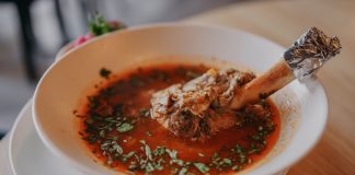 Delicious lamb shank soup garnished with fresh herbs, perfect for a cozy meal.