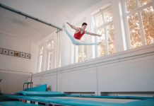BREAKING: Unique Fitness Classes to Try in Jersey City and Hoboken Young sportsman in sportswear doing split in air while jumping on trampoline in gym