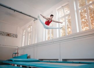 BREAKING: Unique Fitness Classes to Try in Jersey City and Hoboken Young sportsman in sportswear doing split in air while jumping on trampoline in gym