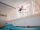 Young sportsman in sportswear doing split in air while jumping on trampoline in gym