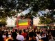 Crowd gathered in İstanbul park watching Euro football on big screen. Energetic summer atmosphere.