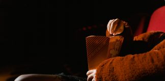 A person enjoying popcorn during a movie at an indoor cinema, sitting comfortably.