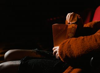 A person enjoying popcorn during a movie at an indoor cinema, sitting comfortably.