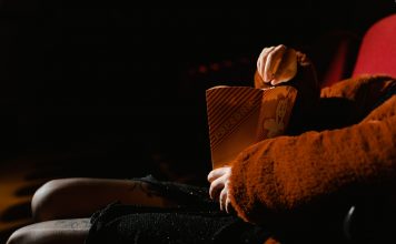 A person enjoying popcorn during a movie at an indoor cinema, sitting comfortably.