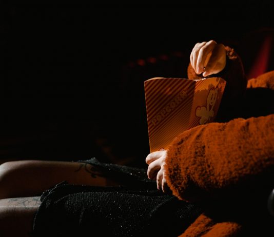 A person enjoying popcorn during a movie at an indoor cinema, sitting comfortably.